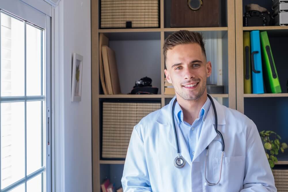 Headshot portrait of smiling young male GP or physician