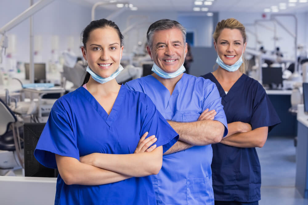 Portrait of smiling co-workers in a line with arms crossed in dental clinic